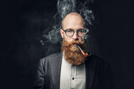 A man smoking pipe over grey background.の写真素材