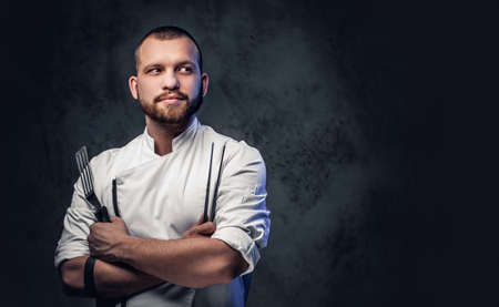 Chef cook holds a knife over dark grey background.の写真素材