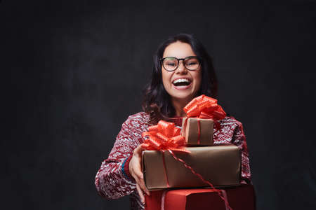 A woman in eyeglasses  holds Christmas gifts.の写真素材