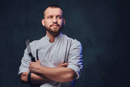 Chef cook holds a knife over dark grey background.の写真素材