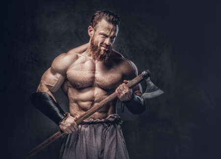 A man holds axe over dark grey background.の写真素材
