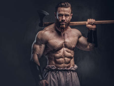 A man holds axe over dark grey background.の写真素材