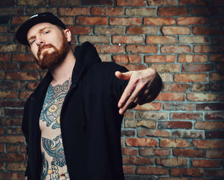 Tattooed bearded male over the wall of a brick.の写真素材