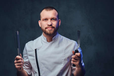 Chef cook holds a knife over dark grey background.の写真素材