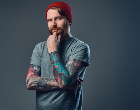 Tattooed bearded male over grey background.