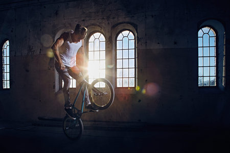 BMX stunt and jump riding in a hall with sunlight.の写真素材