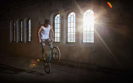 BMX stunt and jump riding in a hall with sunlight.の写真素材