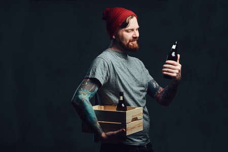 A man holds a wooden box with beer bottles.