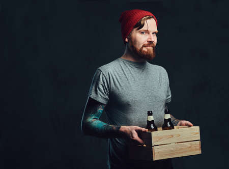 A man holds a wooden box with beer bottles.