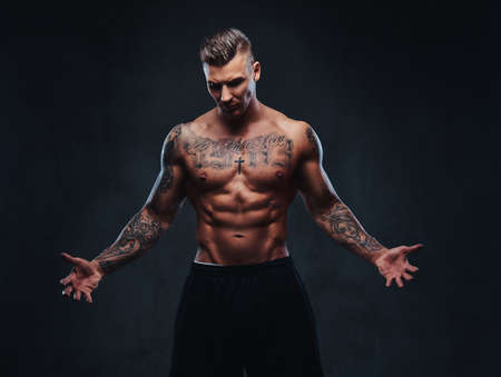 A muscular tattooed man on a dark background.の写真素材
