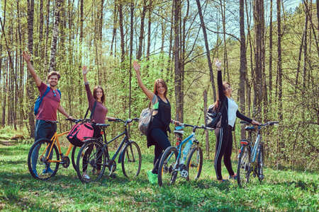 Group of young friends hiking through the forest with bikesの写真素材