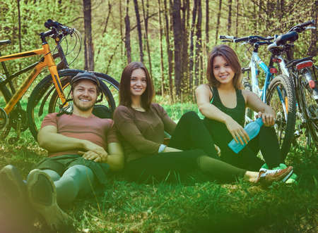 Group of young friends hiking through the forest with bikesの写真素材