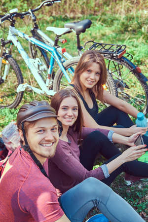 Group of young friends hiking through the forest with bikesの写真素材