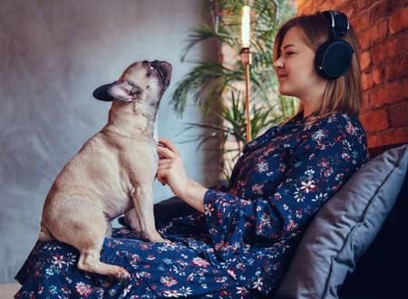 Happy blonde in casual clothes listening music and care a cute pの写真素材