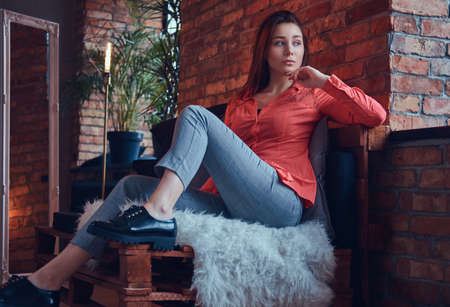 A charming brunette in casual clothes sitting in a room with lof