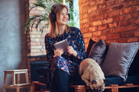 Portrait of a happy charming blonde with the tablet and headphoneの写真素材