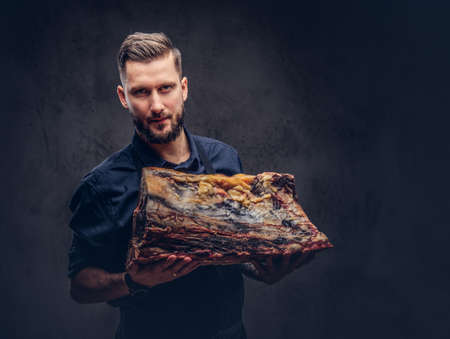 Professional butcher holds a big piece raw smoked meat. Isolatedの写真素材