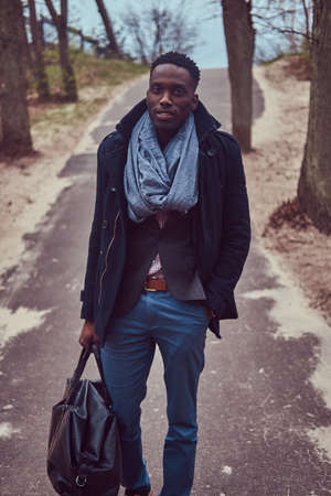 Stylish African-American guy in casual clothing with a bagの写真素材