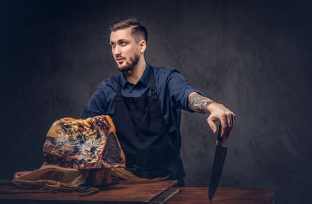 Professional butcher holds a knife standing with raw smoked meat