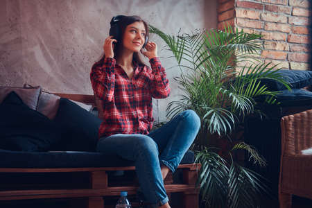 Portrait of a sexy brunette in a flannel shirt and jeans listeniの写真素材