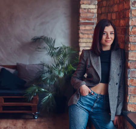 Portrait of a sexy slim young female in a jacket and jeans leaniの写真素材