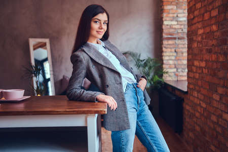 Portrait of a sexy brunette leaning on a table in a room with loの写真素材