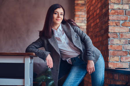 Portrait of a sexy brunette leaning on a table in a room with loの写真素材