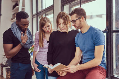 Group of young multiracial students working with books and phoneの写真素材