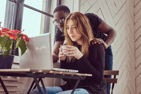 A young student couple working with a laptop at a window.の写真素材