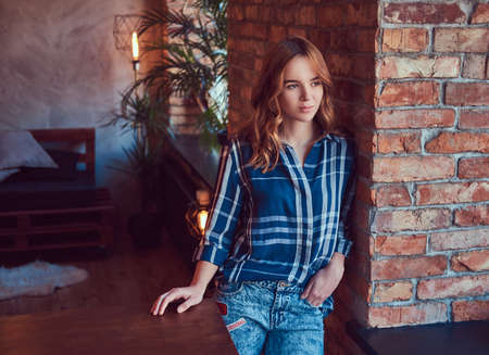 Close-up portrait of a young hipster girl leaning against a bricの写真素材