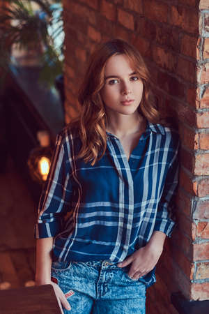 Close-up portrait of a young hipster girl leaning against a bricの写真素材