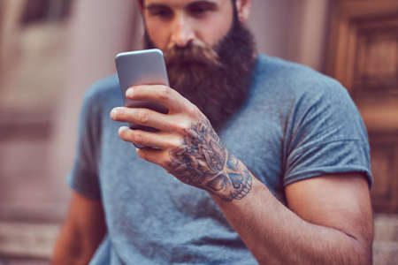 A handsome hipster male with a stylish beard with a tattoo on his armの写真素材