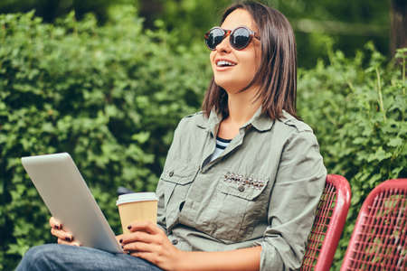 Hipster woman in a sunglasses with a coffee and tablet computer