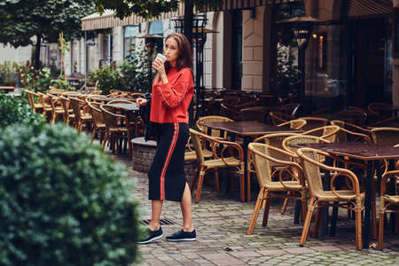 Fashionable brunette in a stylish clothing has fun near the cafeの写真素材