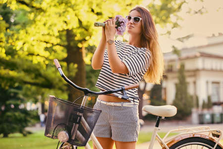 An attractive brunette female with a bicycle in the city park.の写真素材