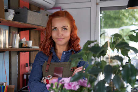 A beauty redhead female barista drinks a coffee, at the coffee shop.の写真素材