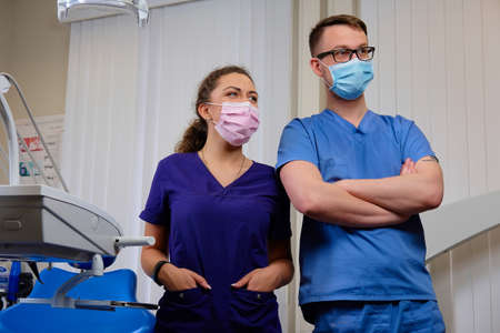 Handsome male dentist with a female assistant, standing in a dentist office.の写真素材
