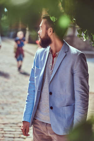 A fashionable bearded male wearing stylish clothes, stands on an antique street in Europe.の写真素材