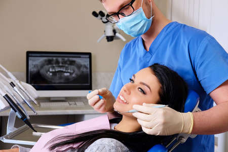 A dentist hands working on young woman patient with dental tools.の写真素材
