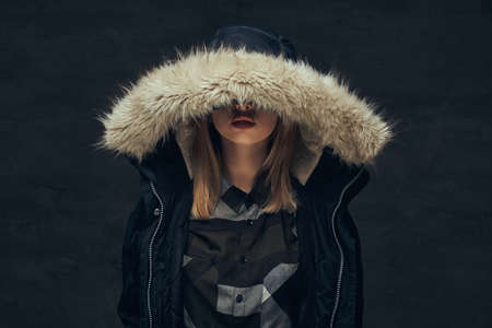 Portrait of a sexy blonde girl in a winter jacket and fleece shirt, standing in a studio.の写真素材