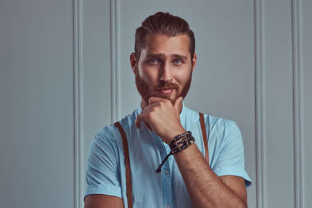 Handsome young retro stylish redhead man in suspenders posing against a white wall in a studio.の写真素材