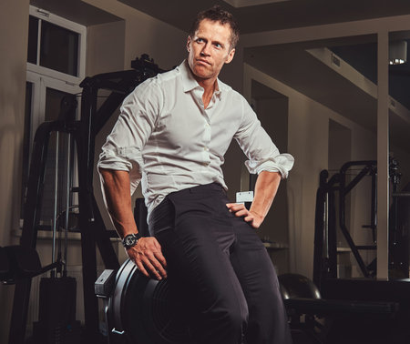 Handsome confident businessman in formal clothes came to the gym for training after a hard days work.の写真素材
