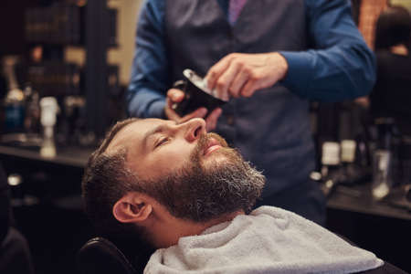 A master hairdresser prepares the face for shaving, deals foam.の写真素材