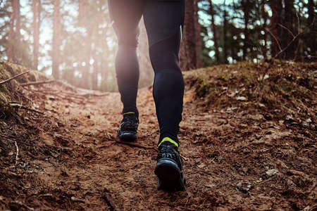 Athlete climbs up the hill along the forest trail. An active way of life.の写真素材