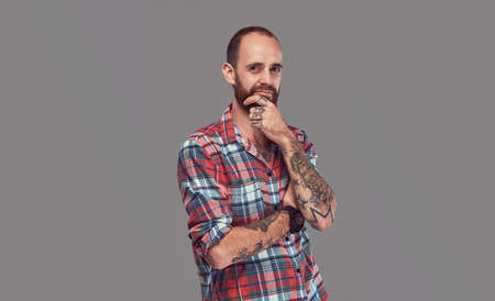 Portrait of a handsome tattooed stylish hipster with a well-trimmed beard in a flannel shirt, posing in a studio.の写真素材