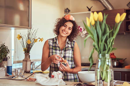 Charming curly Hispanic girl cooking in her kitchen.