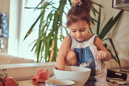 Sweet little cute girl learns to cook a meal in the kitchen.の写真素材