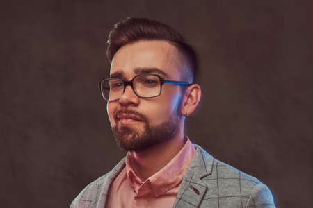 Close-up portrait of a confident stylish bearded man with hairstyle and glasses in a gray suit and...