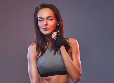 Slim fitness brunette woman in a gray sportswear posing in a studio.の写真素材