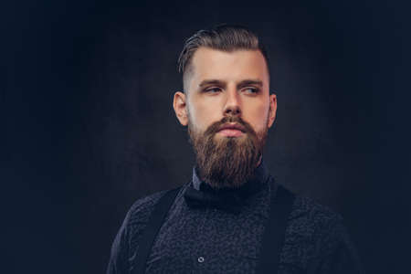 Portrait of a handsome old-fashioned hipster in a blue shirt and suspenders, posing in a studio.